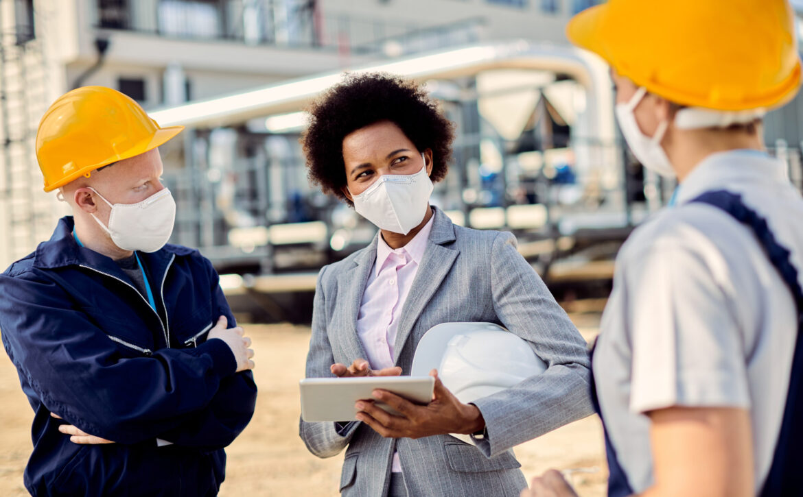 African American building contractor talking to civil engineers